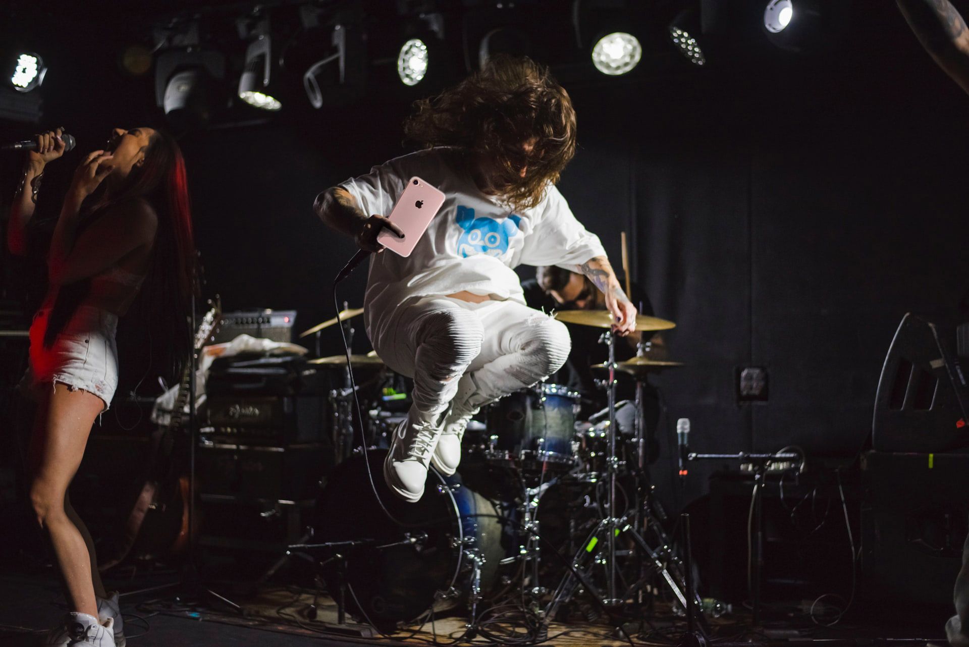 Rock concert with dude holding a pink mobile phone while jumping